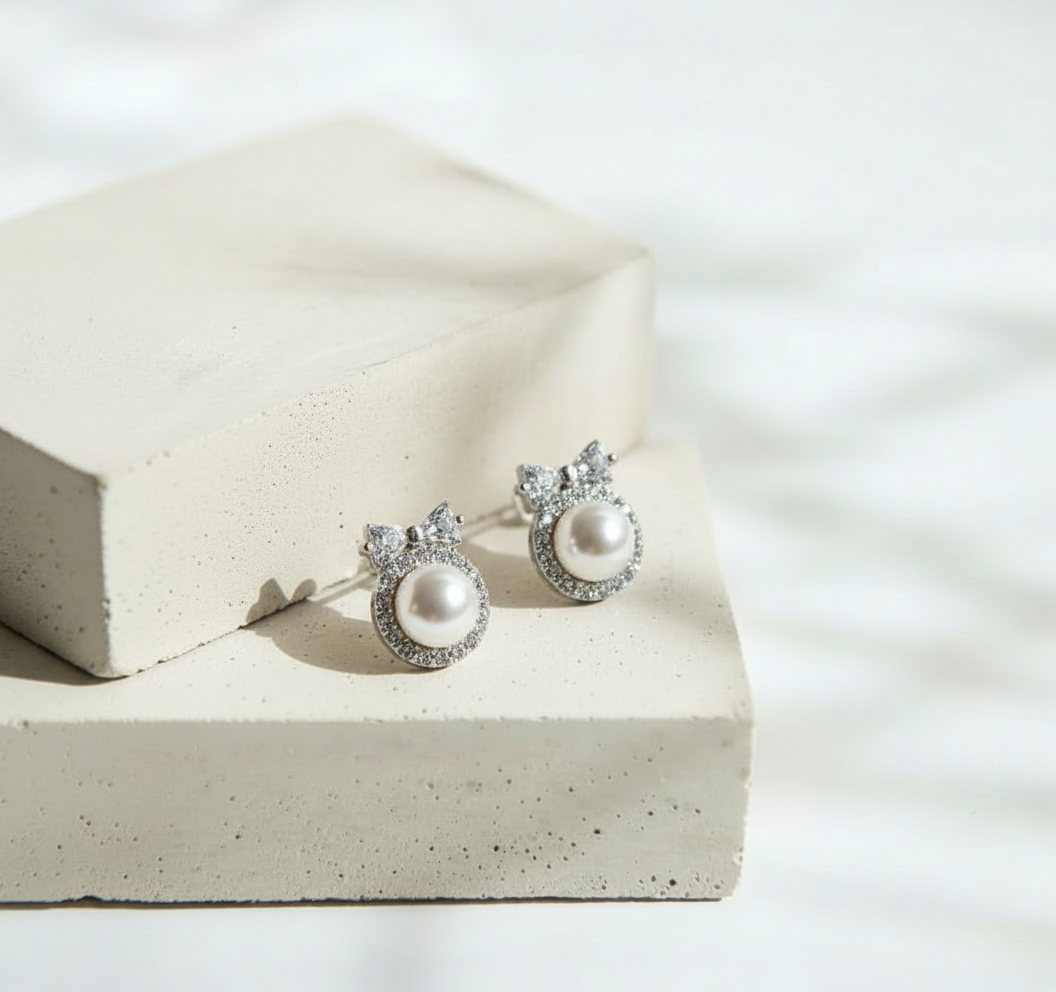 Aretes de Perla Blanca con Moño Dorado de Brillos - Acero Inoxidable