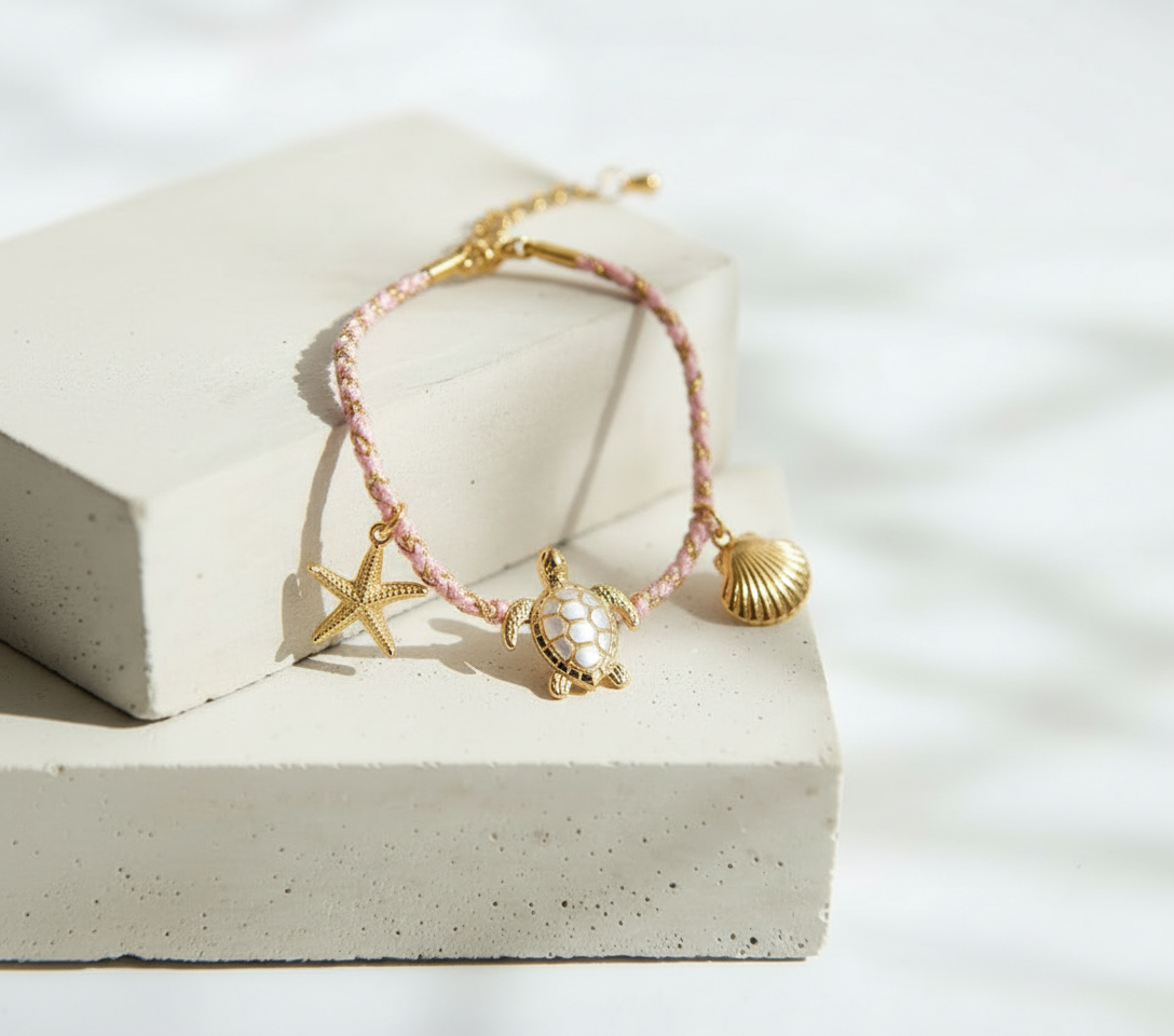 Pulsera Tejida Rosa y Blanca con Dijes Dorados de Tortuga Concha y Estrella de Mar - Acero Inoxidable